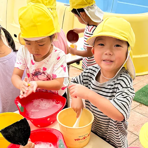 洗面器やバケツに材料を入れ工作する園児たち