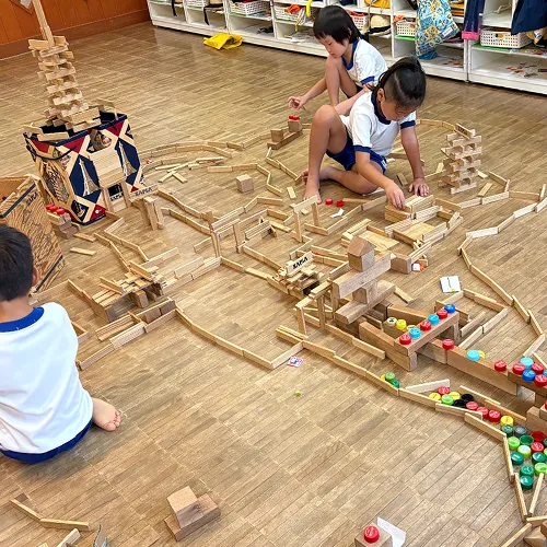 積み木などで大きな建物など作り遊ぶ園児たち
