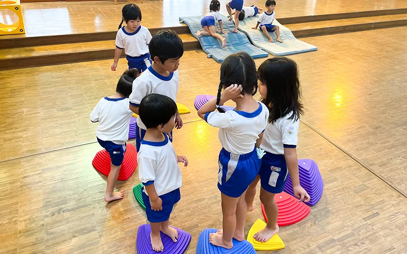 園児たちが輪になり遊具で遊ぶ様子。話し合いをしている。